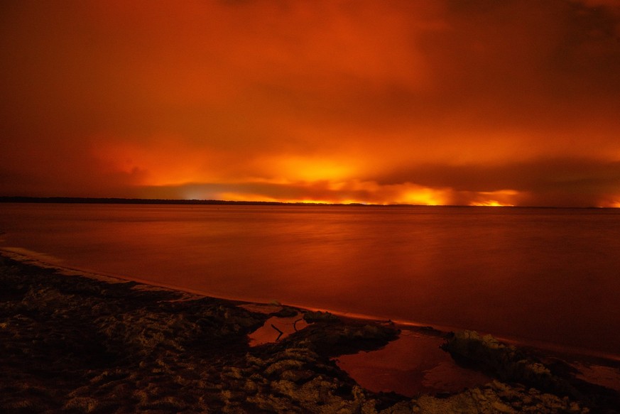 Wildfires in France Drive 250,000 People from Their Homes - Gironde The sky glows deep red over Lake Moutchic as the Lège-Cap-Ferret wildfire illuminates the horizon in Gironde, France on July 25, 202 ...