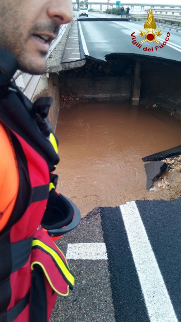 A firefighter inspects a damaged bridge on the Santa Lucia stream along the road from Cagliari to Capoterra village, on the Sardinia island, Italy, Wednesday, Oct. 10, 2018. Torrential rains have been ...