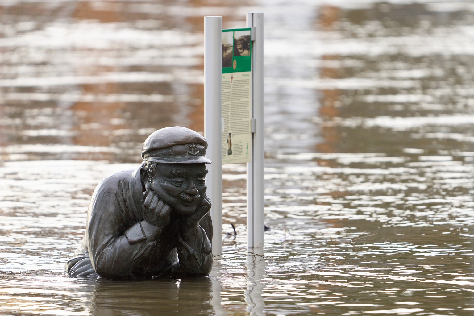 25.12.2023, Rheinland-Pfalz, Lahnstein: Der Bareschesser, die Bronzestatue eines Lahnstein Originals, ist vom vom Hochwasser umsp�lt.Die Lahn f�hrt wieder Hochwasser. Angesichts anhaltender Regenf�lle ...