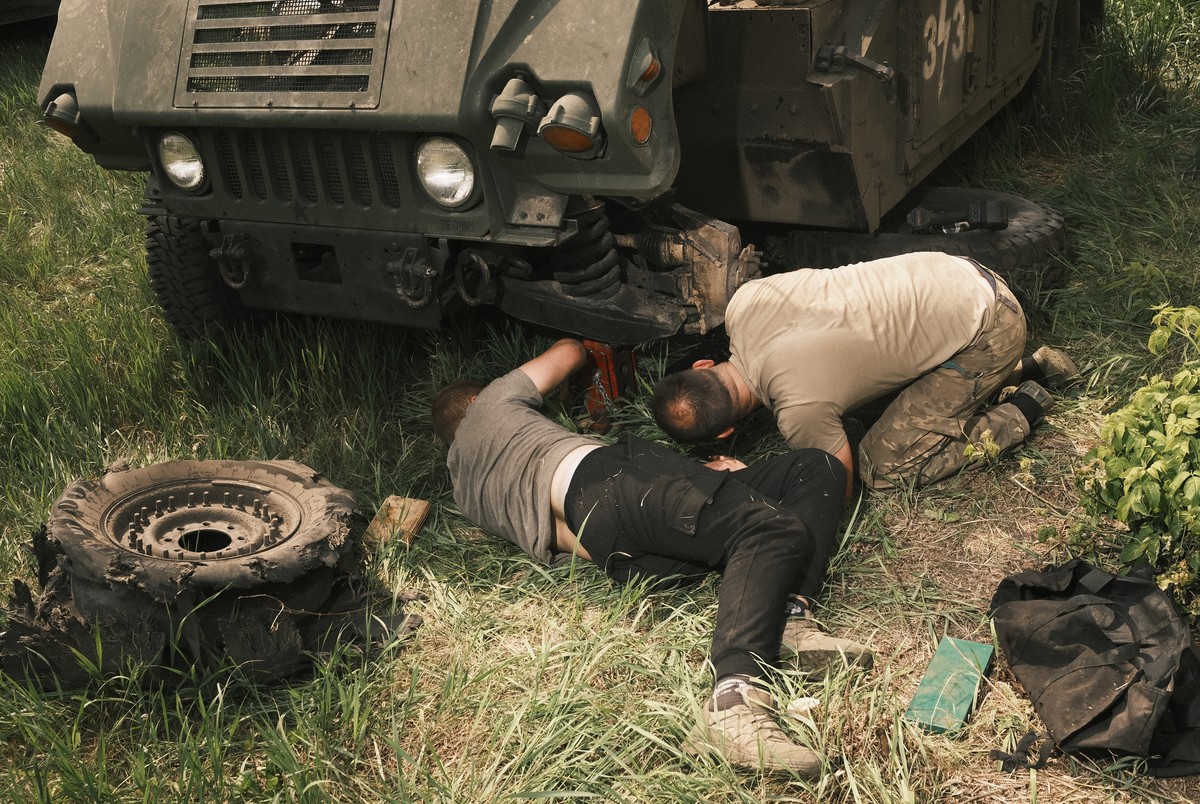 epa11336041 Two men replace a damaged wheel of a Humvee truck on the outskirts of Vovchansk, Kharkiv region, northeastern Ukraine, 12 May 2024, amid the Russian invasion. More than 4,000 residents fro ...