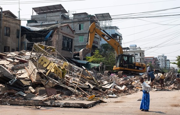 epa12001392 People look at a collapsed building following an earthquake in Mandalay, Myanmar, 31 March 2025. More than 1,700 people have been killed and thousands injured after a 7.7-magnitude earthqu ...