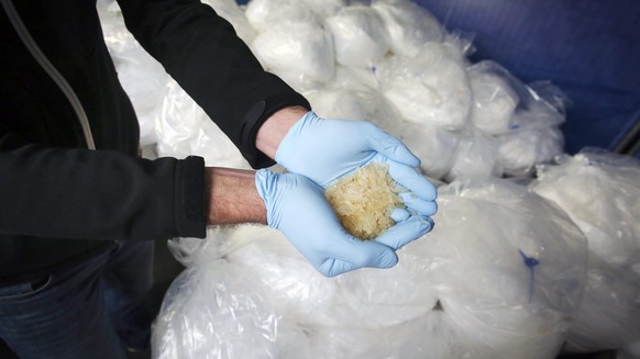 epa04487940 An investigator of the Federal Criminal Police Office (BKA) holds some of 2.9 tons of seized Crystal Meth on display for media in Wiesbaden, Germany, 13 November 2014. Investigators from s ...