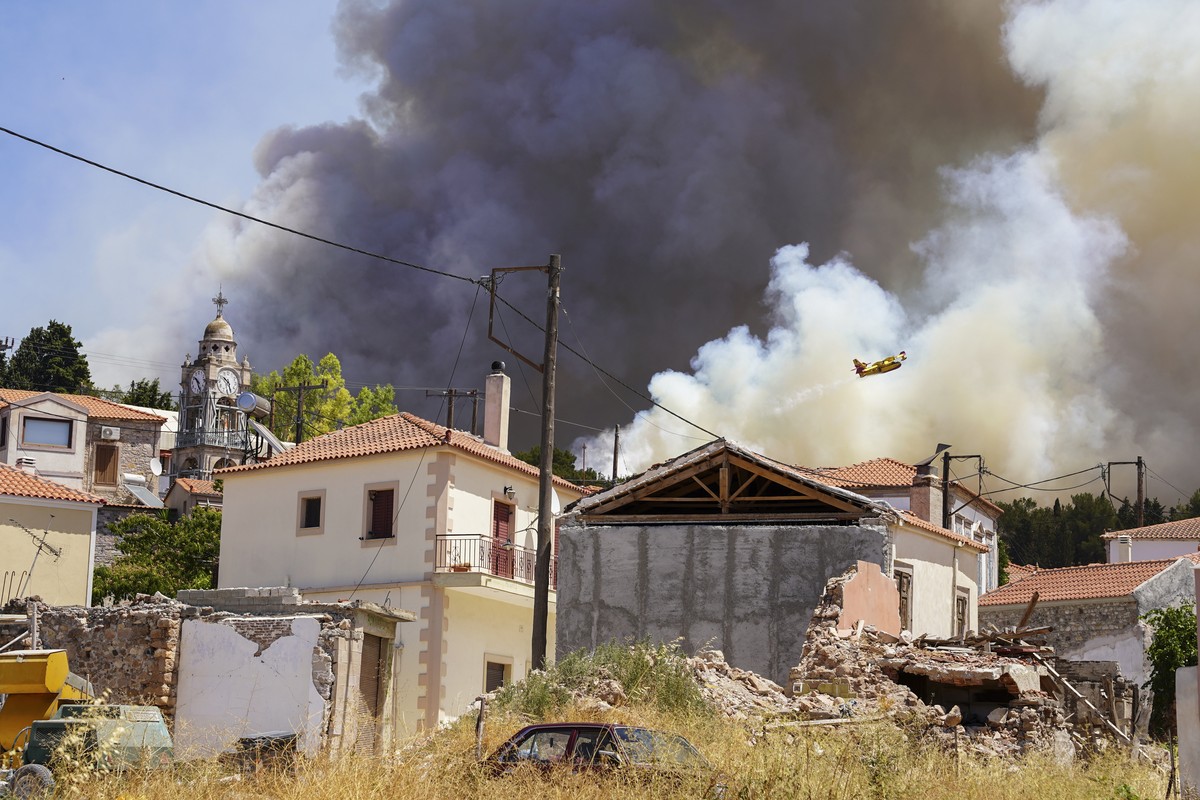 A firefighter aircraft drops water over a forest fire as smoke rises near Vrisa village, on the eastern Aegean island of Lesbos, on Sunday, July 24, 2022. A fire that broke Saturday morning on the Gre ...