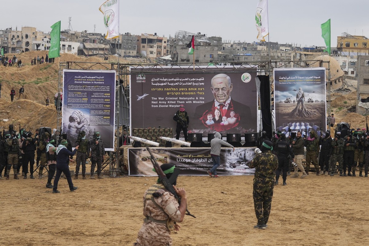 Militants stand around the coffins containing the bodies of hostages, from right to left, Shiri Bibas, her two children, Ariel and Kfir and Oded Lifshitz, who was 83 when he was abducted before their  ...