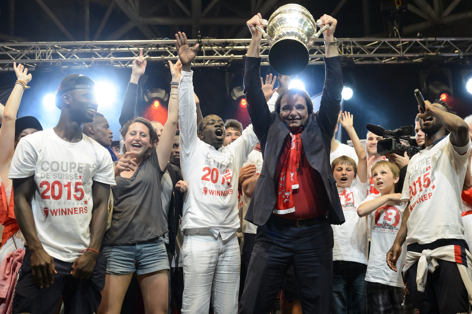 FC Sion president Christian Constantin, center with the trophy, celebrates on stage with player Moussa Konate, left, and teamates in front of their fans after they won the Swiss Cup final soccer match ...
