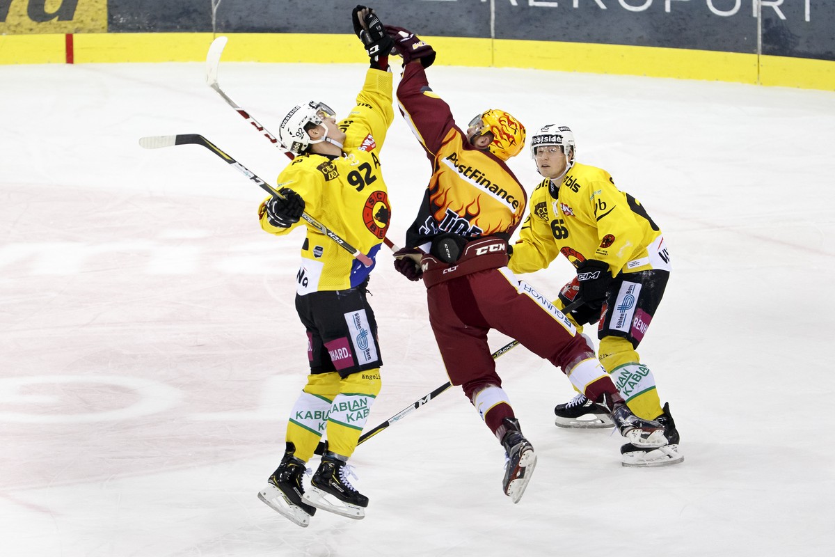Geneve-Servette's center Tanner Richard, center, catches the puck with hand between Bern's center Gaetan Haas, left, and defender Ramon Untersander, right, during a National League regular s ...
