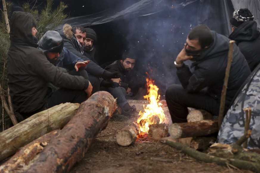 Migrants warm themselves near fire gathering at the Belarus-Poland border near Grodno, Belarus, Sunday, Nov. 14, 2021.Poland&#039;s prime minister says Poland, Lithuania and Latvia are considering ask ...