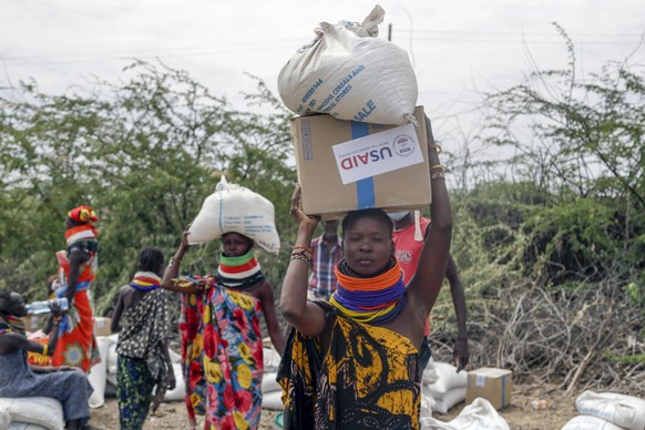 Local residents carry boxes and bags of food distributed by the United States Agency for International Development (USAID), in Kachoda, Turkana, Northern Kenya, Saturday, July 23, 2022. Saman...
