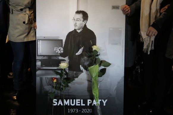 People hold a photo of the history teacher Samuel Paty , who was beheaded last week, during a memorial march in homage to him, Tuesday, Oct.20, 2020 in Conflans-Sainte-Honorine, northwest of Paris. Sa ...