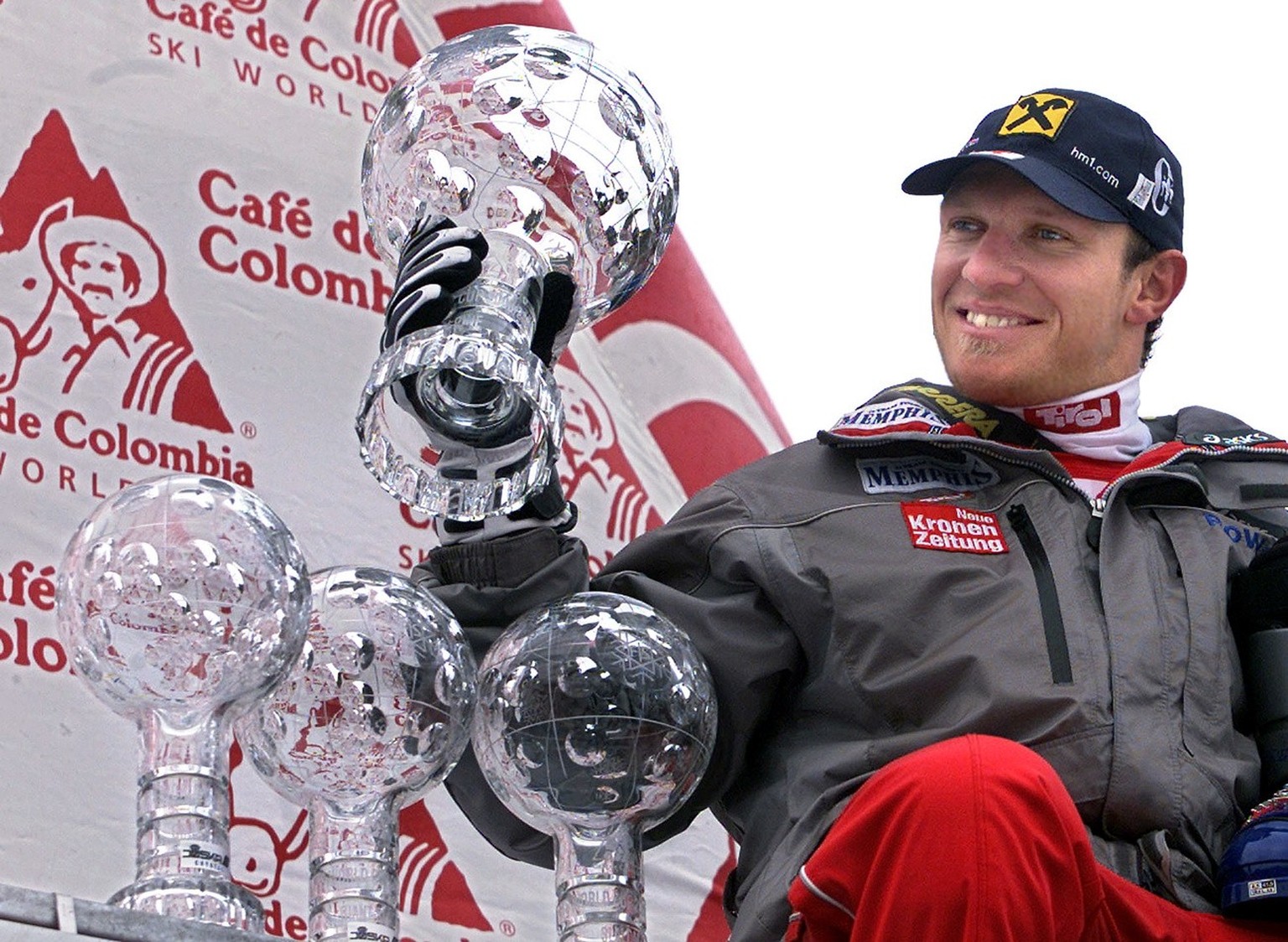 Austria&#039;s ski star Hermann Maier sits next to his Super-G, downhill and Giant Slalom world titles&#039; throphies as he hoists his Overall Skiing World Cup throphy after winning in a combined tim ...
