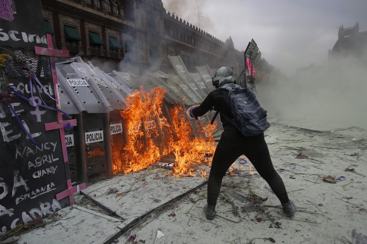A demonstrator throws burning gasoline at a police shield wall that is closing a breach on a barricade protecting the National Palace during a march to commemorate International Women's Day and p ...