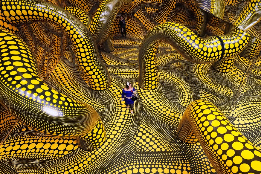 People walk through the artwork 'Infinity Mirrored Room' during a preview of the new major exhibition of legendary Japanese artist Yayoi Kusama at the Museum Ludwig in Cologne, Thursday, Mar ...