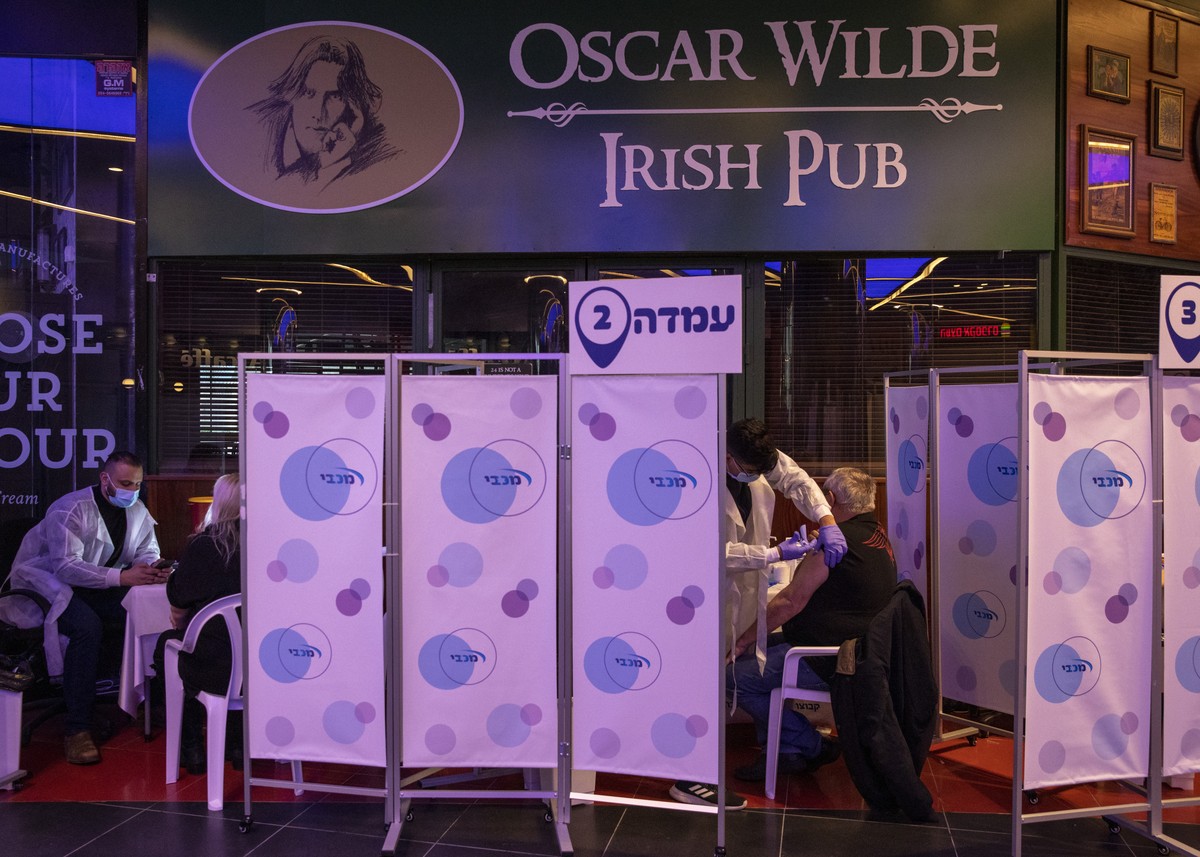 A medical professional administers a second dose of the Pfizer COVID-19 vaccine to a man at a movie theater turned into a coronavirus vaccination center in Netanya, Israel, Thursday, Jan. 28, 2021. (A ...