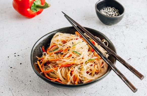 Vegan Funchoza salad. Asian salad with fresh vegetables: carrot, bell pepper, cucumber, with sesame seeds. Asian food. White background. Top view