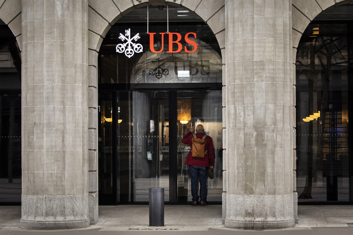 A man looks into a window of the headquarters of Swiss banks Credit UBS in Zurich, Switzerland on Sunday March 19, 2023. (KEYSTONE/Michael Buholzer).