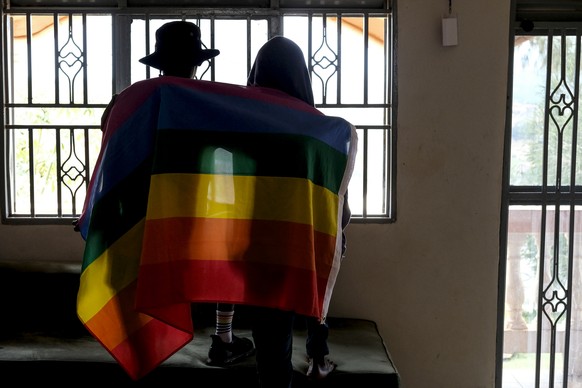 FILE - A gay Ugandan couple cover themselves with a pride flag as they pose for a photo in Uganda on March 25, 2023. Ugandan lawmakers passed a new version of an anti-gay…