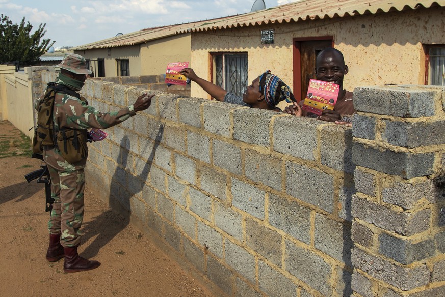 A soldier hand out flyers about the novel coronavirus to a resident on the streets of Soweto, South Africa, Thursday, April 23, 2020, as the country remains in lockdown for a fourth week in a bid to c ...