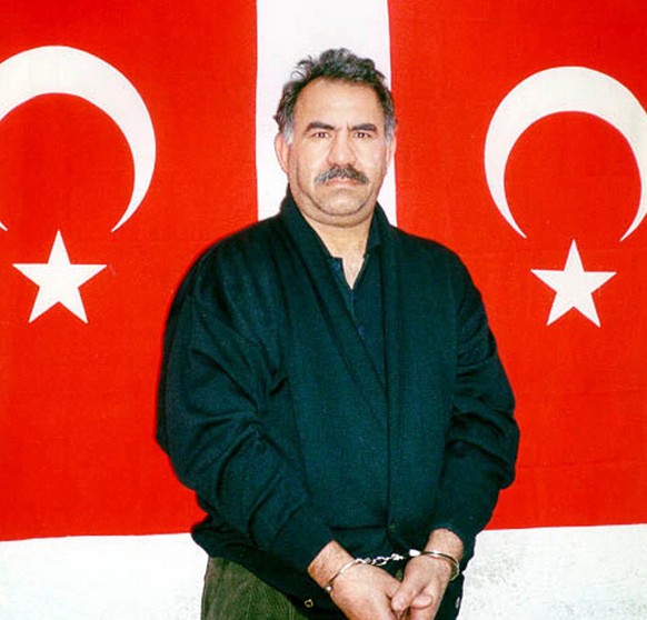 Kurdish rebel leader Abdullah Ocalan poses in front of Turkish flags before being interrogated by Turkish officials at the prison-island of Imrali in this image provided by the Turkish Intelligence Se ...