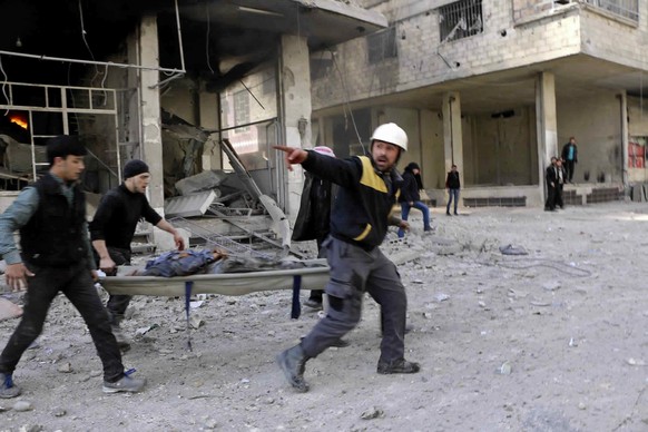 This photo released Tuesday Feb. 20, 2018, provided by the Syrian Civil Defense group known as the White Helmets, shows members of the Syrian Civil Defense group carrying a man who was wounded during  ...