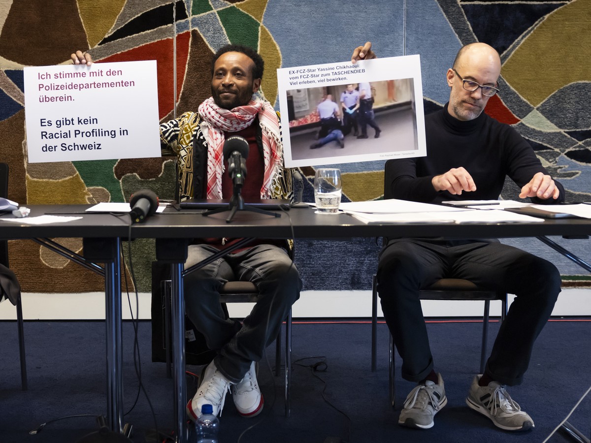 Mohamed Wa Baile, Mitte, haelt neben Anwaeltin Magda Zihlmann, links, und Tarek Naguib, Jurist und Mitglied der Allianz gegen Racial Profiling, rechts, Plakate hoch, waehrend einer Medienkonferenz der ...