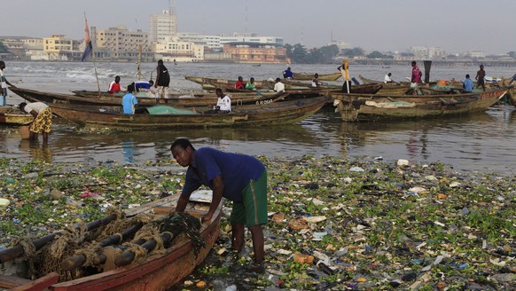 A fisherman stands amidst city trash brought in by the tide, as he prepares to launch his fishing boat, in the Akpakpa Dodomey neighborhood of Cotonou, Benin Thursday, Nov. 17 2011. Pope Benedict XVI  ...