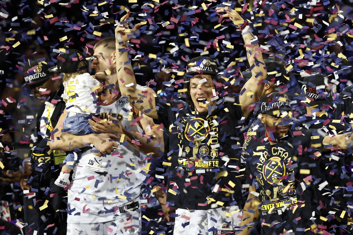 epa10687841 Denver Nuggets forward Aaron Gordon (C), Denver Nuggets center Nikola Jokic (L) and his daughter Ognjena, and other teammates celebrate on the NBA Championship podium as confetti drops aft ...