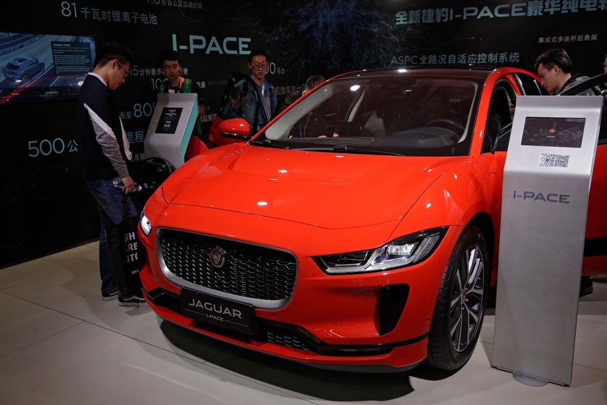 FILE- In this April 25, 2018, file photo journalists and visitors look at the Jaguar electric-powered I-Pace model showcases at the China Auto Show during the media day in Beijing. While Tesla grapple ...