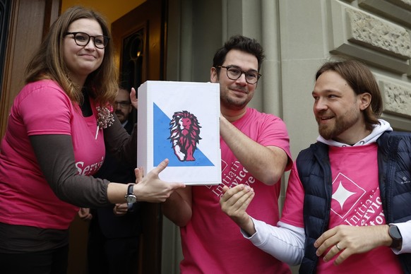 Kampagnenleiterin und Co-Praesidentin Noemie Roten, links, Komitee-Mitglied Michel Rickhaus, Mitte, und Co-Praesident Quentin Adler, rechts, reichen die Schachteln mit den gesammelten Unterschriften w ...