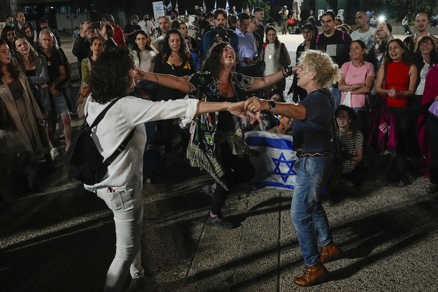 People react as they hear the news of the release of 13 Israeli hostages held by Hamas in the Gaza strip, in Tel Aviv, Israel, on Friday, Nov. 24, 2023. Friday marks the start of a four-day cease-fire ...