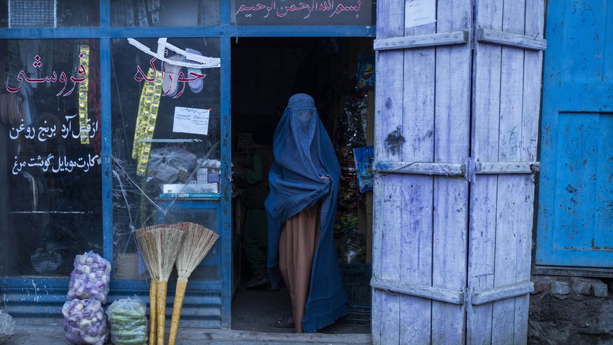 An Afghan women exits a convenience shop in Kabul , Afghanistan , on Sunday, Dec. 5, 2021. Since the chaotic Aug. 15 Taliban takeover of Kabul, an already war-devastated economy once kept alive by int ...
