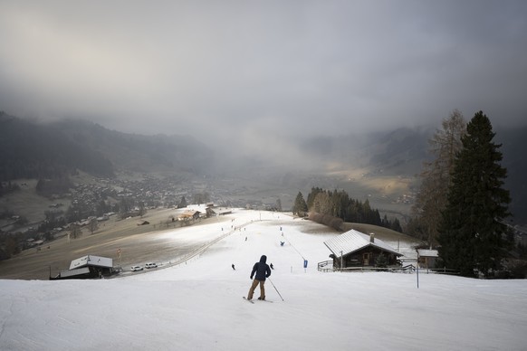 Skifahrer fahren eine kuenstlich beschneite Piste mit Schneekanonen auf den Skipisten der Gstaad Bergbahnen am Dienstag, 30. Dezember 2025, zwischen dem Rinderberg und Zweisimmen. (KEYSTONE/Anthony An ...