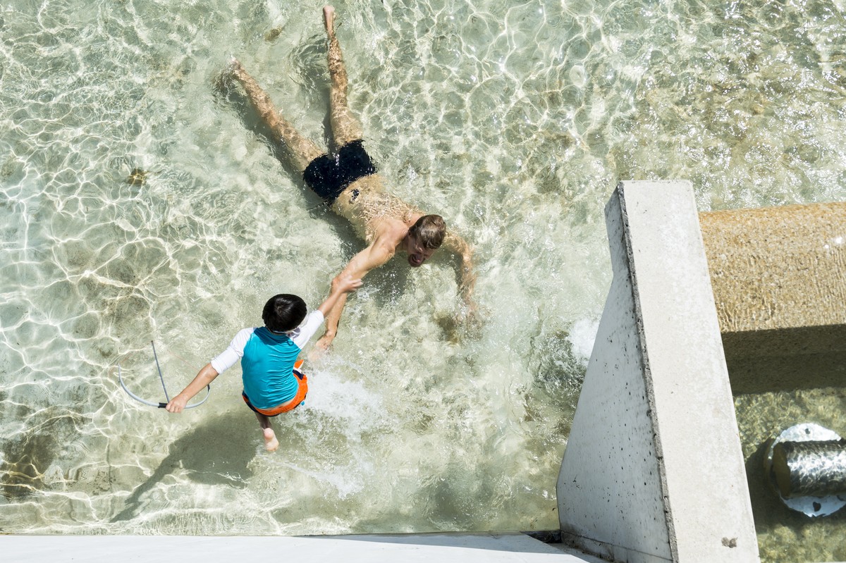 Un homme se fraiche et joue dans l'eau avec un garcon dans la fontaine sur la Place de la Navigation, ce mercredi 1 juillet 2015 a Lausanne. (KEYSTONE/Dominic Steinmann)