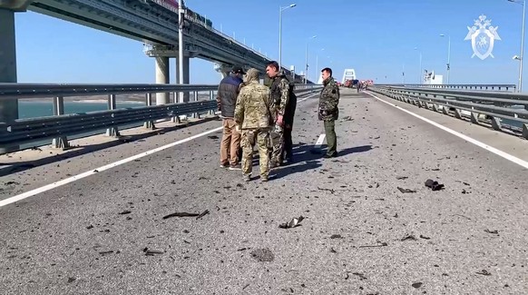 In this image taken from video released by the Russian Investigative Committee, employees of the Russian Investigative Committee work at the scene of a damaged part on Crimean Bridge connecting Russia ...