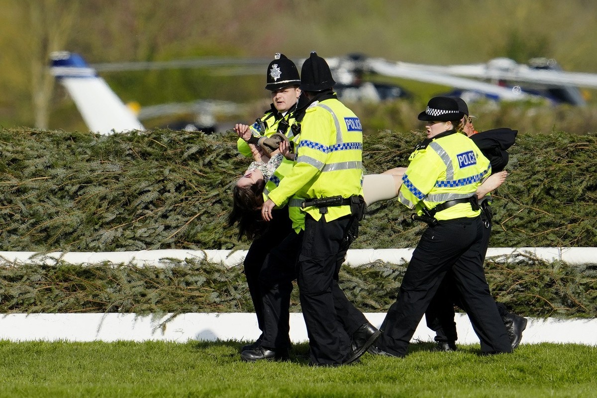 Members of the police forces remove a protester before the start of the Grand National horse race at Aintree Racecourse Liverpool, England, Saturday, April 15, 2023. The iconic Grand National race whi ...
