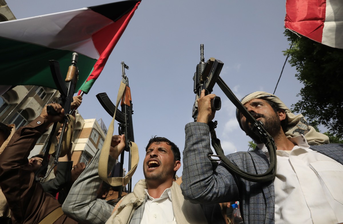 Des militants crient leur soutien au Hamas en brandissant leurs armes.