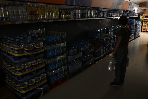 epa12060435 A woman holds two water container at a supermarket as a blackout hits Spain and Portugal in Castellon, northeastern Spain, 28 April 2025. A massive blackout has hit large parts of Spain an ...