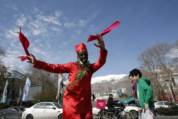 epa11229196 An Iranian man dressed as Haji Firouz, the traditional herald of Nowruz, dances and collects money among people shopping at a street market on the eve of 'Nowruz', the Persia...