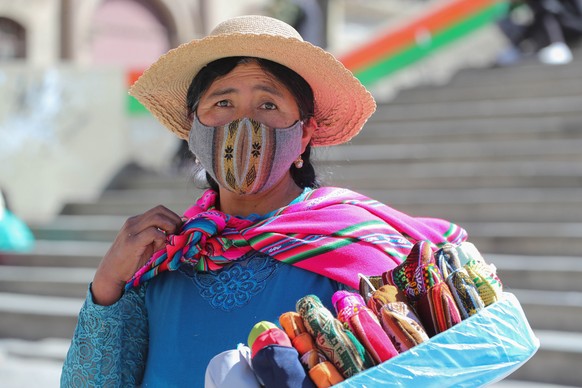 epa08496644 An Aymara woman sells face masks during a quarantine decreed due to the COVID-19 pandemic at a central square in La Paz, Bolivia, 19 June 2020. The Aymara, aka Aimara are an indigenous nat ...