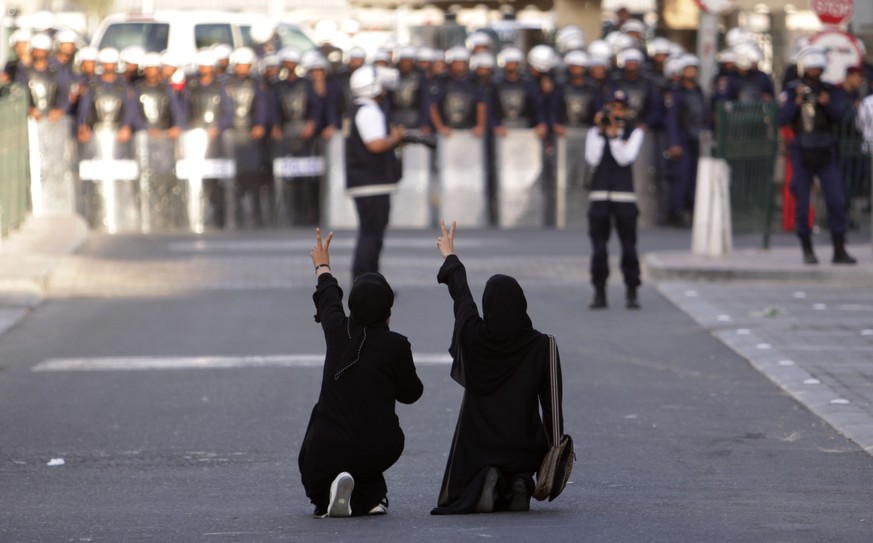 FILE - In this file photo from Wednesday, January 18, 2012, Bahraini anti-government protesters kneel in the street and gesture to riot police in Manama, Bahrain.  Bahraini security forces tortured detainees...