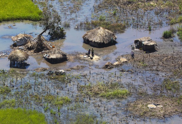 FILE - In this Tuesday March 26, 2019 file photo, a family stand outside their submerged huts near Beira, Mozambique. Beira's mayor Davis Simango dreamed about protecting his people from climate ...