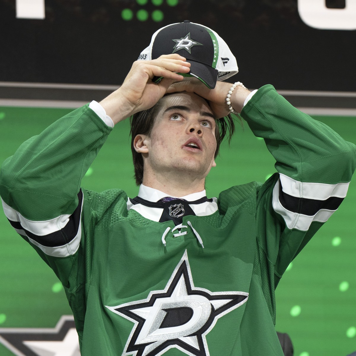 The Dallas Stars' 18th pick, Lian Bichsel, puts on his cap during the first round of the NHL hockey draft Thursday, July 7, 2022, in Montreal. (Ryan Remiorz/The Canadian Press via AP)