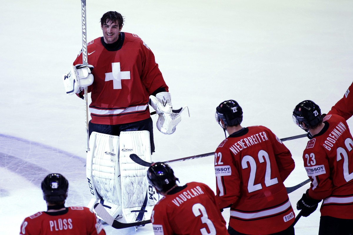 Switzerland's goaltender Reto Berra, top, is celebrated by his teammates, from left, Martin Pluess, Julien Vauclair, Nino Niederreiter and Simon Bodenmann, after their victory over USA, during th ...