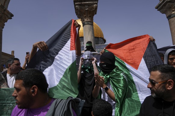 Palestinians hold the Palestinian national flag and the flag of the Hamas militant group during a protest by the Dome of Rock at the Al-Aqsa Mosque compound in the Old City of Jerusalem during the Mus ...