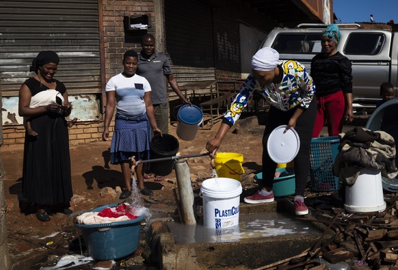 Besonders der informelle Sektor leidet unter den Corona-Massnahmen: Frauen warten auf Wasser an einem Brunnen in Johannesburg.
