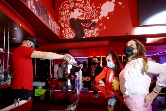 epa09292583 A barman serves a drink to a woman inside a disco club in Madrid, Spain, 21 June 2021 (issued 22 June 2021). Discos and night clubs reopened on 21 June with capacity restrictions in Madrid ...