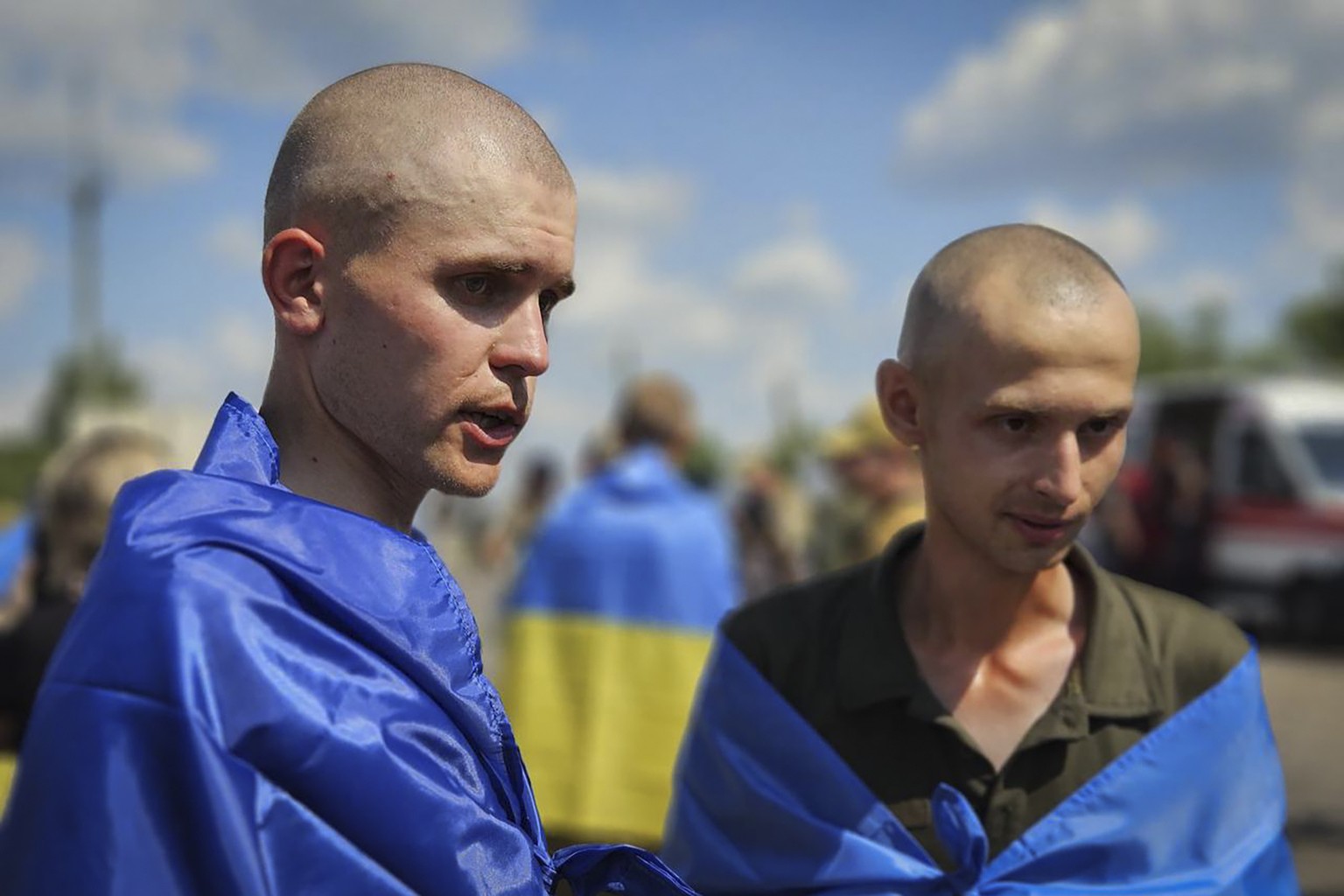 In this photo provided by the Ukrainian Presidential Press Office on Wednesday, July 17, 2024, Ukrainian prisoners of war wrapped in national flags pose for a photo after a prisoners exchange at an un ...