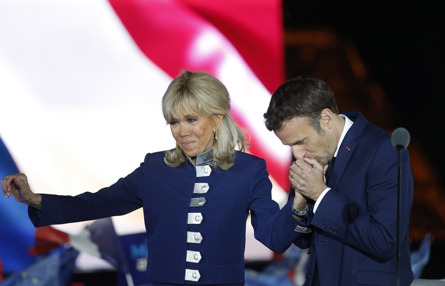 epaselect epa09907435 French President Emmanuel Macron and his wife Brigitte Macron celebrate on the stage after winning the second round of the French presidential elections at the Champs-de-Mars aft ...