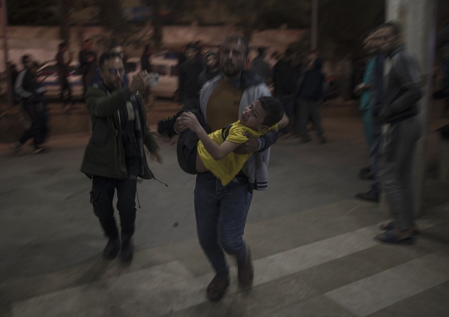 epa11035178 A Palestinian man carries an injured boy to the Nasser Hospital in Khan Yunis, southern Gaza Strip, 17 December 2023, following an Israeli artillery strike. More than 18,000 Palestinians a ...