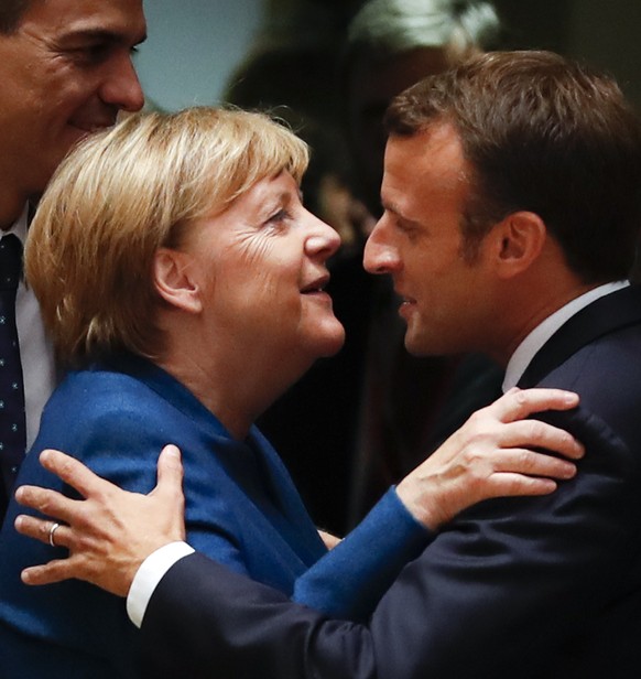 German Chancellor Angela Merkel, left, is greeted by French President Emmanuel Macron during a round table meeting at an EU summit in Brussels, Wednesday, Oct. 17, 2018. European Union leaders are con ...