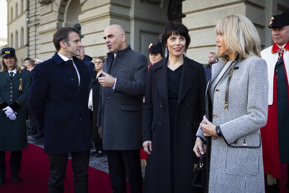 French President Emmanuel Macron, Swiss President Alain Berset, Muriel Zeender Berset and Brigitte Macron, from left, discuss in front of the Federal Palace, the Swiss Parliament building, in Bern, Sw ...
